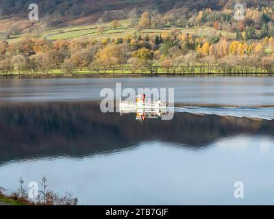 The Ullswater Ferry creates a wake on the calm flat waters of Ullswater in the English Lake District in Autumn, England, November, UK Stock Photo
