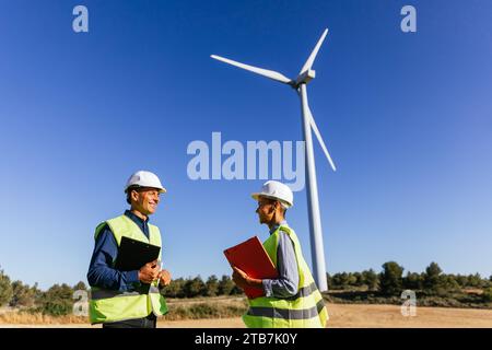 Renewable energy engineers on a field with wind turbines. Stock Photo