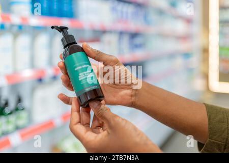 Cropped hand of anonymous person holding bottle and checking information on prescribed product label in drugstore Stock Photo