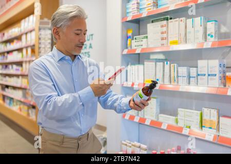 Senior man using app on mobile phone for checking information about prescribed product in drugstore in blurred background Stock Photo