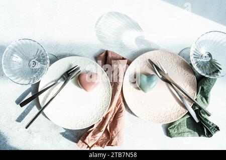 Top view of ceramic plate with cutlery and napkin with heart shaped decor crystal placed on concrete surface at kitchen table for meal during Valentin Stock Photo