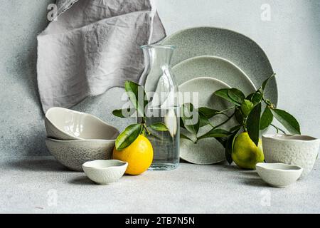 A sophisticated table setting featuring fine ceramic dishes, fresh lemons, and pears on a textured linen backdrop. Stock Photo