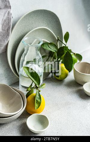 A sophisticated table setting featuring fine ceramic dishes, fresh lemons, and pears on a textured linen backdrop. Stock Photo
