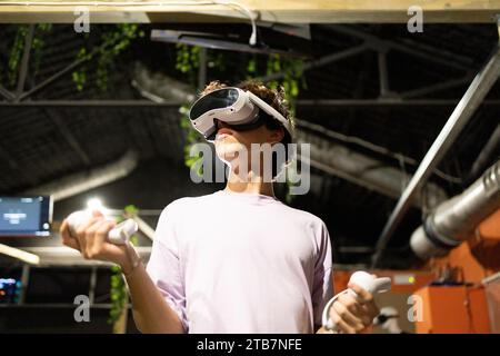 A young person is deeply immersed in a virtual reality simulation, using VR controllers with focus and intensity. Stock Photo