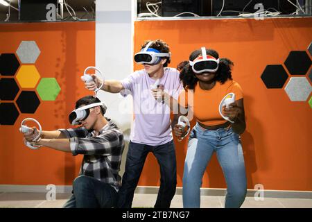 Young multiracial friends fully immersed in a virtual reality gaming session wielding controllers and wearing VR headsets Stock Photo