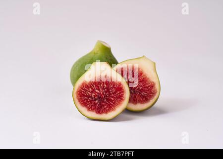 Ripe figs with one cut in half to reveal the juicy red interior, arranged against a clean, white backdrop. Stock Photo