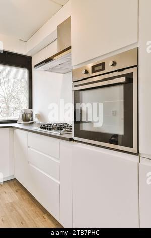 Interior of modern kitchen with built in microwave and white cabinets in spacious contemporary light house Stock Photo