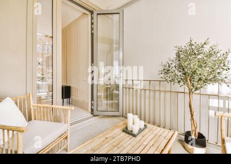 Wooden chair and coffee table with houseplant arranged in balcony outside window of contemporary apartment Stock Photo