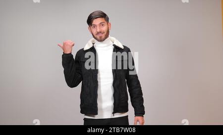 A young man striking a surprised pose against a gray background. Stock Photo