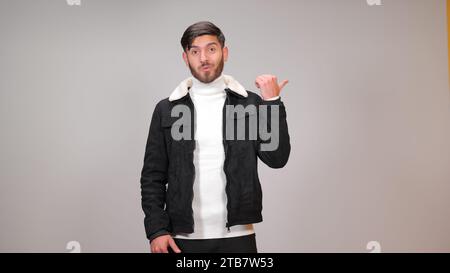 A young man striking a surprised pose against a gray background. Stock Photo