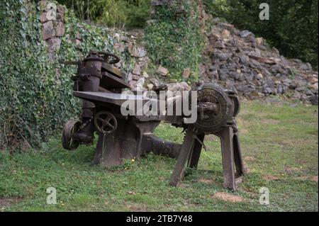 Remains of rusty machines from an old factory abandoned in the war, lathe and cutting table and electric motor with water pump Stock Photo