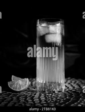 Dark and Stormy cocktail in black and white with ice and lemon in high ball glass Stock Photo