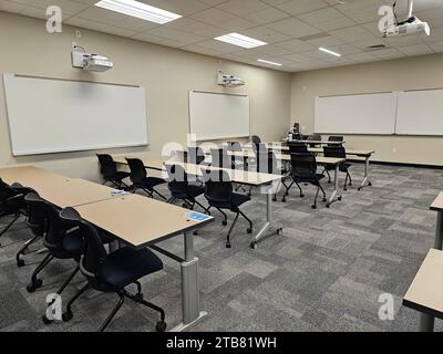 An empty classroom interior, with rows of desks and a projector suspended from the ceiling Stock Photo