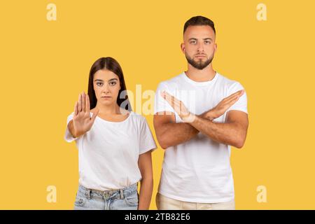 Angry strict millennial european man and lady in white t-shirts make stop gesture with hand Stock Photo