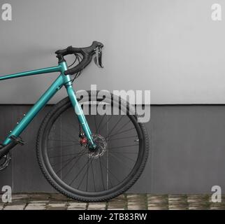 Front part of gravel bike on grey wall background. Modern brand new bicycle for cross country. Stock Photo