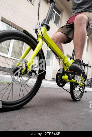 Low angle view of man riding compact folding bike for urban commuting. Stock Photo