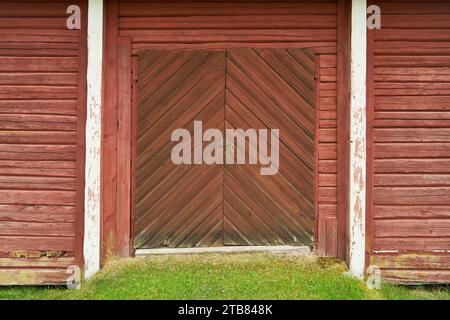 Old wooden barn door with red painted wood planks in village Stock Photo