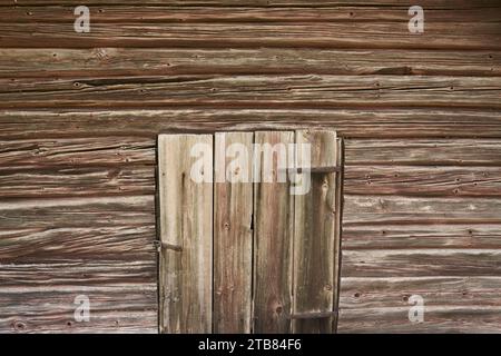 Old weathered wooden barn door in brown wood wall Stock Photo