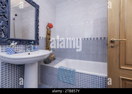 A modern bathroom with a blue cabinet, tile and stone back splash, and  marble tiling the floor / shower. Stock Photo