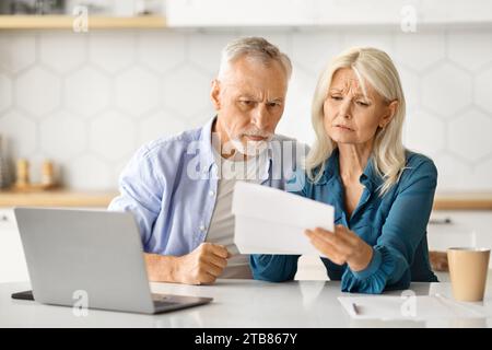 Upset Elderly Spouses Checking Financial Documents While Calculating Family Budget At Home Stock Photo