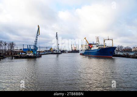 Many tall cargo cranes barges and ships, stand on the banks of River. Baltic Sea. Stock Photo