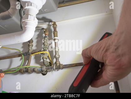 Man using a portable LED lamp or LED torch to inspect domestic plumbing Stock Photo