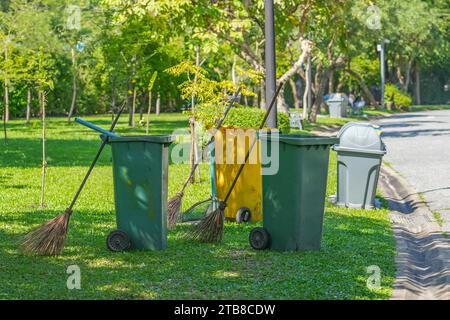 Green yellow Trash can and broom in a public city park Stock Photo