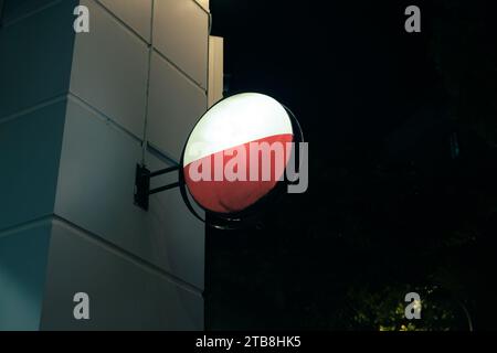 Illuminated empty signboard lighting hanging on edge of store building in the night Stock Photo