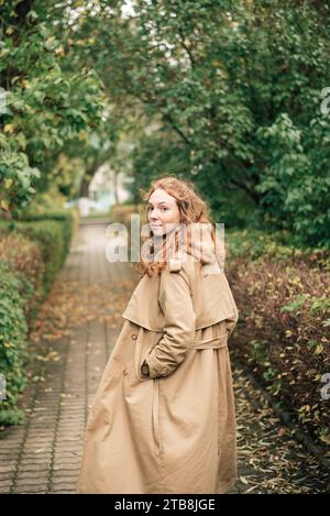 red-haired girl in a beige trench coat in autumn Stock Photo