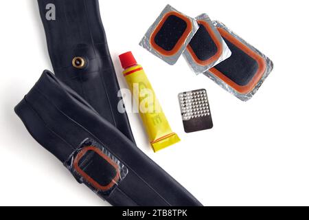 Taped bicycle tube, a set of patches and a tube of glue isolated on a white background. Bike Repair Kit Stock Photo