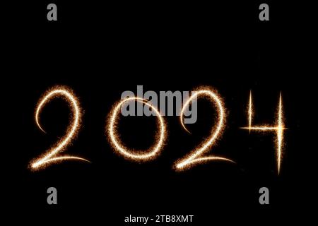 2024 happy new year text written with Sparkle firework on black background, seasonal backdrop with sparklers Stock Photo