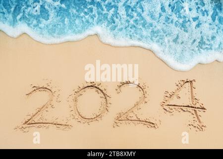 Happy New Year 2024 text on tropical beach sand and turquoise water of caribbean sea Stock Photo