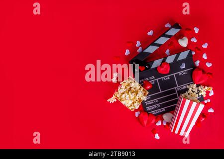 Romantic date on Valentine's Day February 14. Love movie marathon, date at cinema theater. Clapperboard, popcorn buckets, heart decor and chocolates o Stock Photo