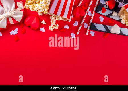 Romantic date on Valentine's Day February 14. Love movie marathon, date at cinema theater. Clapperboard, popcorn buckets, heart decor and chocolates o Stock Photo