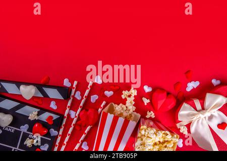 Romantic date on Valentine's Day February 14. Love movie marathon, date at cinema theater. Clapperboard, popcorn buckets, heart decor and chocolates o Stock Photo