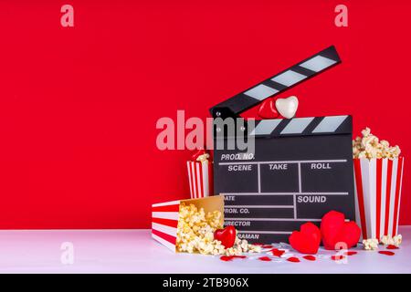 Romantic date on Valentine's Day February 14. Love movie marathon, date at cinema theater. Clapperboard, popcorn buckets, heart decor and chocolates o Stock Photo