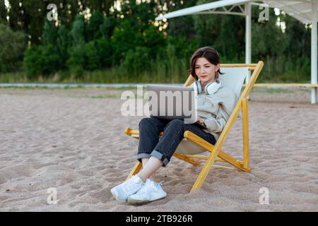 Happy woman smiling working on laptop on a beach Stock Photo