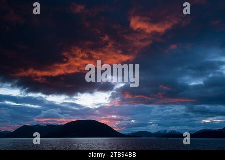 Storm clouds glow over mountains and ocean at sunset over Chatham Strait, Inside Passage, Alaska, USA; Alaska, United States of America Stock Photo