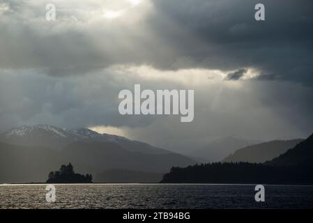 Icy Strait and sunlight shining through storm clouds and reflecting on the tranquil water below, Inside Passage, Alaska, USA Stock Photo