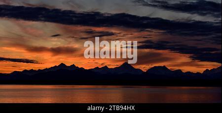 Mountain peaks silhouetted at sunrise, with a dramatic red glowing sky with dark clouds in Glacier Bay National Park and Preserve, Inside Passage, ... Stock Photo