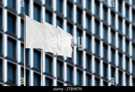 Three white corporate flags waving in the wind against blurry office building. Blank flag mockup to add any logo, symbol or sign Stock Photo