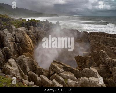 High tide and a strong swell produce a blast of ocean mist at a rocky blowhole; Greymouth, Punakaiki, South Island, New Zealand Stock Photo