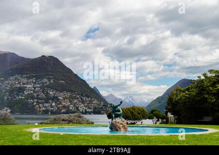 Lugano, Switzerland - March 14, 2023: Fountain by Lake Lugano with statue in the middle of blue water in Ticino canton of Switzerland Stock Photo