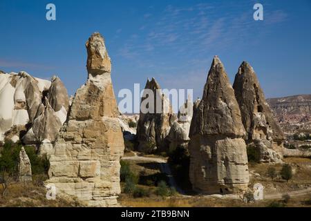 Cave Houses carved into the volcanic rock formations, Fairy Chimneys, against a bright blue sky near the town of Goreme in Pigeon Valley, Cappadoci... Stock Photo