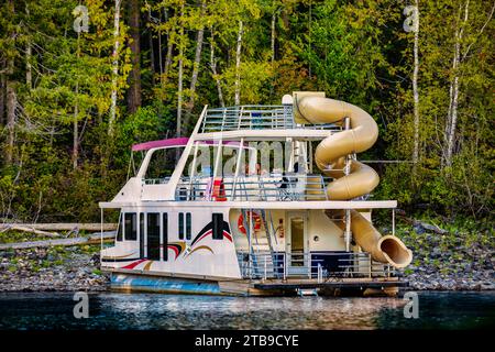 A family enjoying a houseboat vacation while parked on the shoreline of Shuswap Lake; Shuswap Lake, British Columbia, Canada Stock Photo