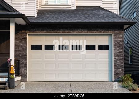 Garage Door. Modern house with garage door that is closed. A perfect neighborhood. Family house with wide garage door and concrete driveway in front. Stock Photo