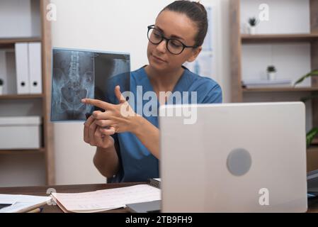 doctor showing X-ray films to patient in laptop, providing patient with an understanding of disease Stock Photo