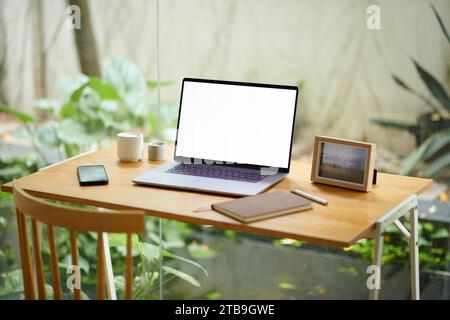 Laptop with empty screen on minimalistic desk in home office decorated with candles and picture frame Stock Photo