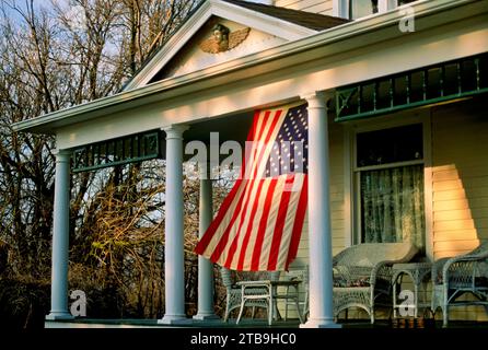 Porch of a historic nineteenth-century farmhouse with American flag; Lancaster County, Nebraska, United States off America Stock Photo