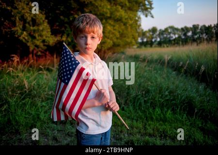 Young, patriotic boy holds up an American flag; Lincoln, Nebraska, United States of America Stock Photo